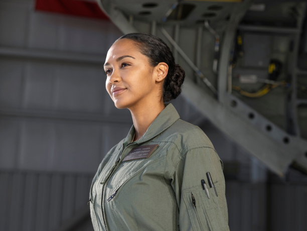 A woman wearing a green work shirt with pens clipped in her sleeve pocket in an airplane hangar