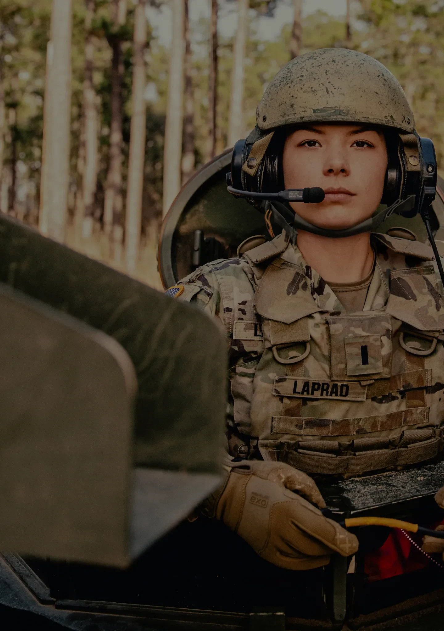 A female armor officer sitting aboard a tank